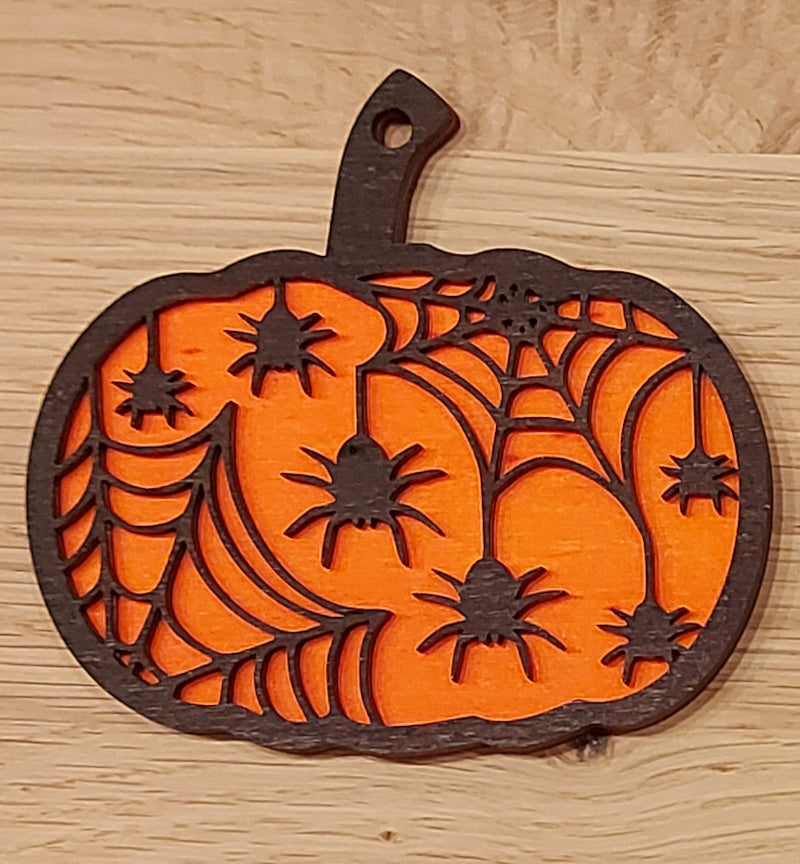 Houten en gekleurde Halloween decoratie. Halloween hanger met gravure van pompoen en spinnen