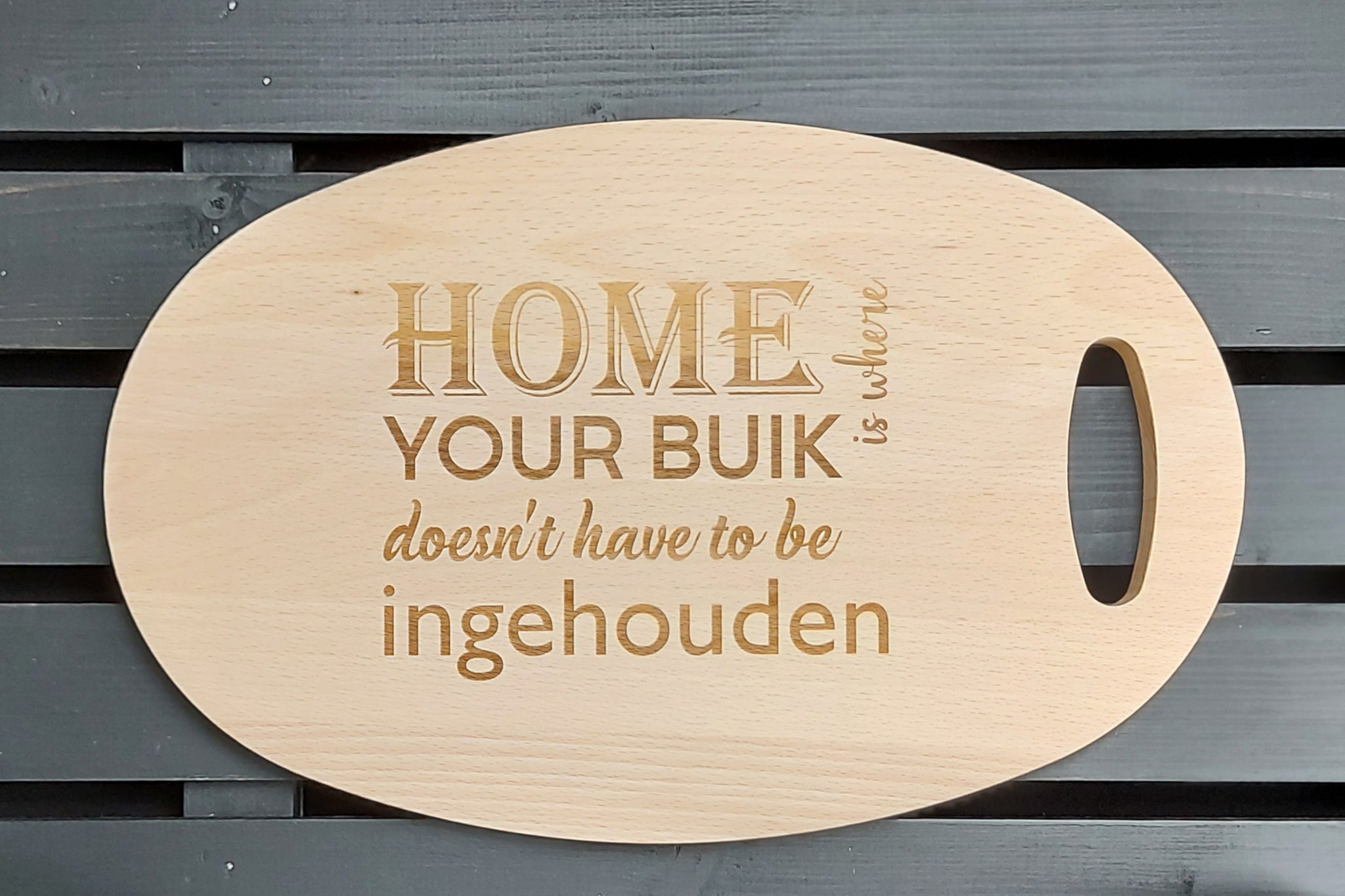 Beuken houten ovalen tapasplank, snijplank, serveerplank. Snijplank handgemaak. Afgewerkt met gravure van 'Home is where your buik doesn't have to be ingehouden'.